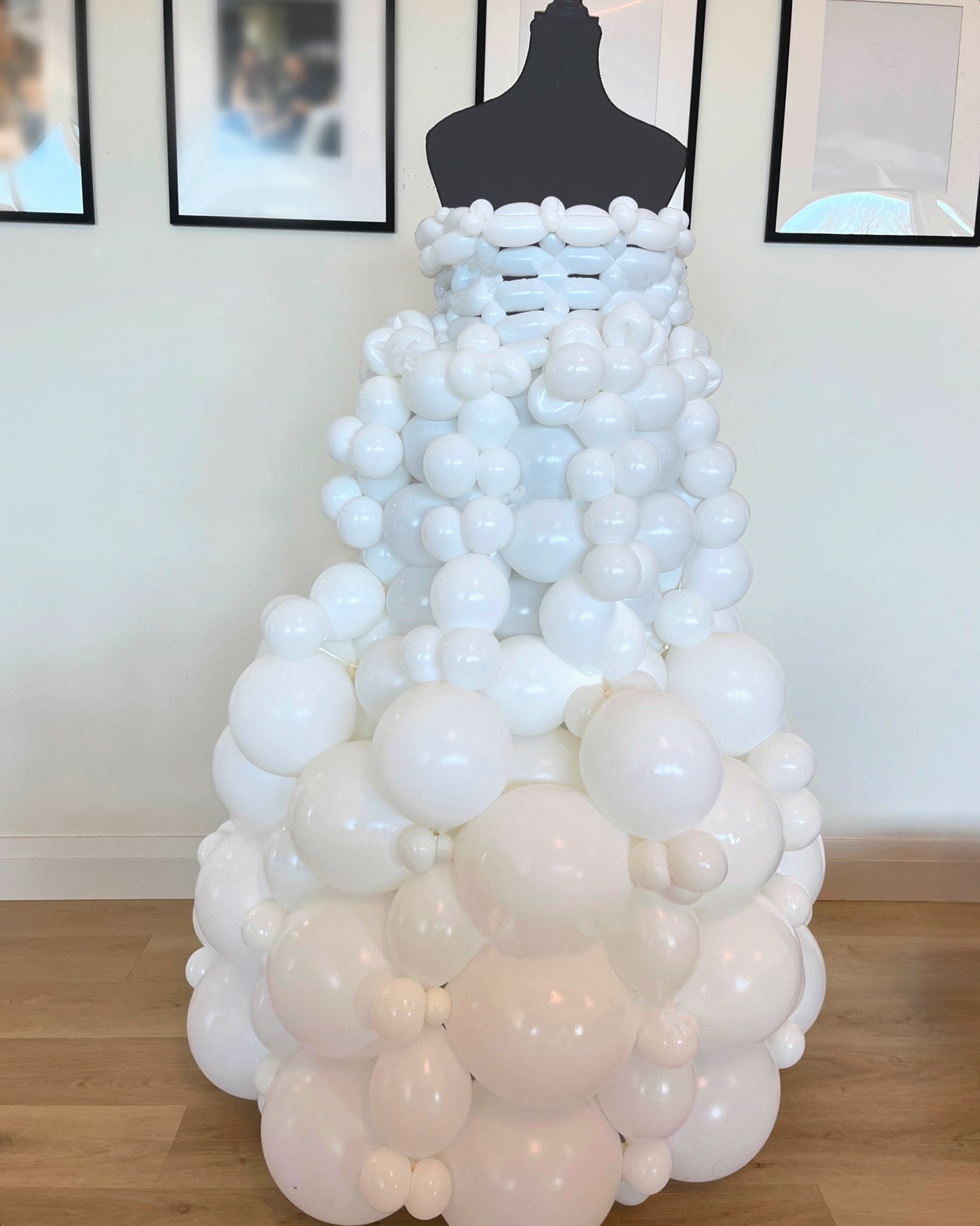 A 3D dress sculpture made out of white balloons, designed to be displayed on a mannequin or as a freestanding piece.